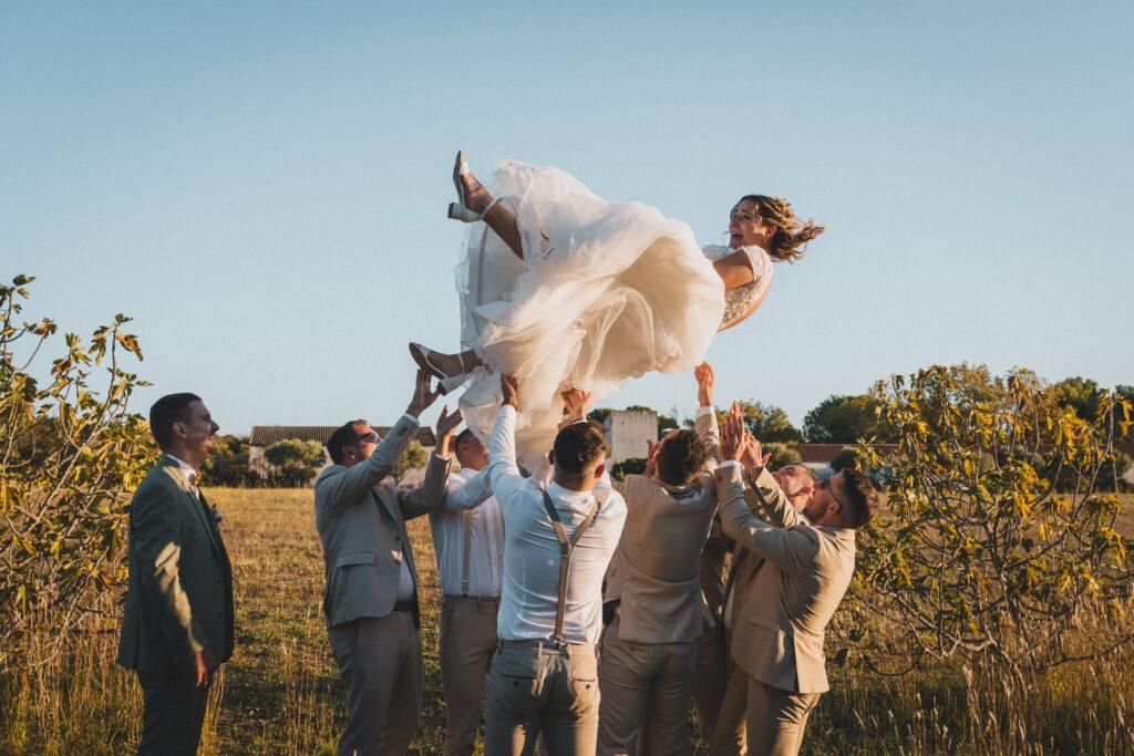 Photo fun des mariés et leurs témoins. La mariée est jetée en l'air par les garçons